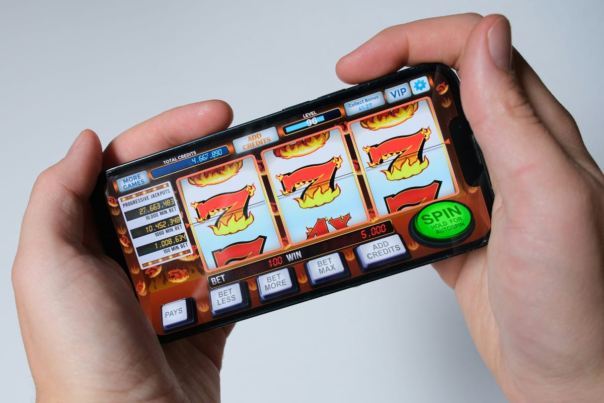 Hands holding a phone with a slot game on screen